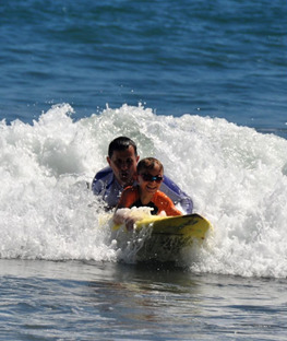 Full colour image of two surfers sharing a belly ride on a board together.