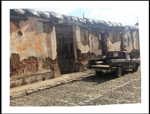 Photo of a rustic pickup truck parked on a cobblestone street. The photo is skewed about 10 degrees counterclockwise. 