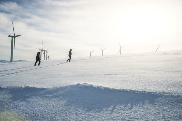 Soldiers walking in a snow covered field of wind turbines.