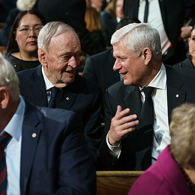 Two men seated in a pew are having a discussion.
