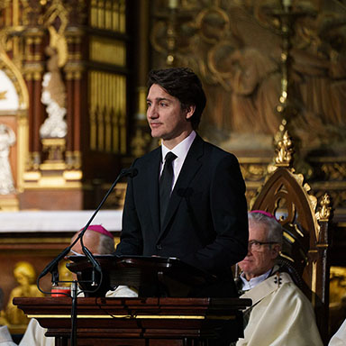 Justin Trudeau reads at the podium in the basilica.
