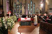 Archbishop Colin Johnson blesses the flag-draped casket of the late Honourable Jim Flaherty. 