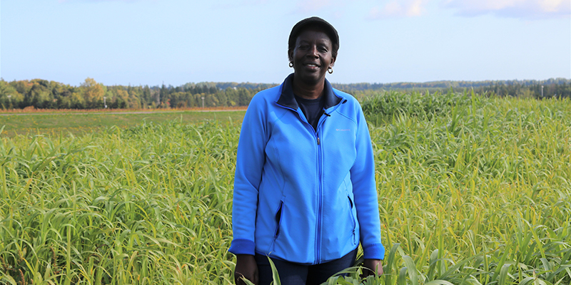 Judith Nyiraneza, sur une terre agricole, pose pour une photo dans un champ.